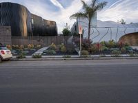 the car is parked on the side of the street with the building behind it and two trees by the side