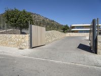 a wooden fence around a driveway gate and entrance way in the mountains near a residential