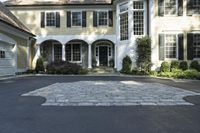 a large two story white house with a front door and a driveway in the street