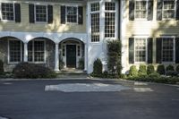 a large two story white house with a front door and a driveway in the street