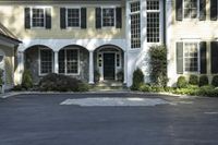 a large two story white house with a front door and a driveway in the street