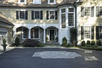 a large two story white house with a front door and a driveway in the street
