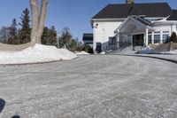 this house has a driveway and well maintained with some snow on it while on the road are trees