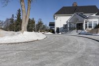 this house has a driveway and well maintained with some snow on it while on the road are trees