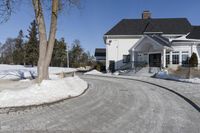 this house has a driveway and well maintained with some snow on it while on the road are trees