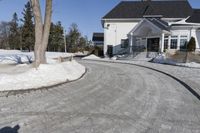 this house has a driveway and well maintained with some snow on it while on the road are trees