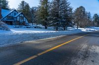 a house on a snowy mountain road near the snow on the ground with evergreens