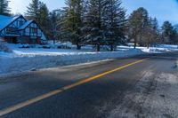 a house on a snowy mountain road near the snow on the ground with evergreens