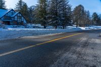 a house on a snowy mountain road near the snow on the ground with evergreens