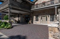 a building has red brick walkway, a stone wall, and two story porches