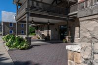 a building has red brick walkway, a stone wall, and two story porches