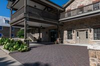 a building has red brick walkway, a stone wall, and two story porches