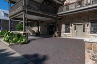 a building has red brick walkway, a stone wall, and two story porches