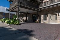 a building has red brick walkway, a stone wall, and two story porches