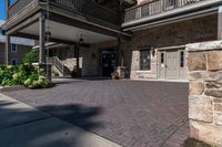 a building has red brick walkway, a stone wall, and two story porches