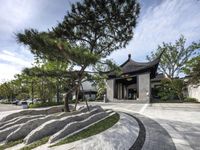 a big asian style building with lots of trees and shrubs in front of it's entrance