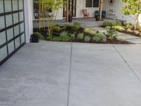 a home with an entryway to a large driveway and plants growing all around the porch