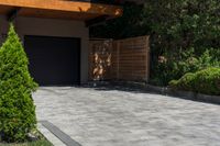 a driveway is shown with a garage door in the distance behind it and landscaping around it