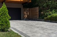 a driveway is shown with a garage door in the distance behind it and landscaping around it