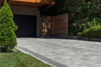 a driveway is shown with a garage door in the distance behind it and landscaping around it