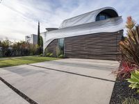 a house with a wooden exterior has a sloping metal facade and is on a grassy area