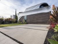 a house with a wooden exterior has a sloping metal facade and is on a grassy area