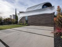 a house with a wooden exterior has a sloping metal facade and is on a grassy area