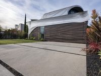 a house with a wooden exterior has a sloping metal facade and is on a grassy area