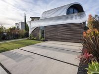 a house with a wooden exterior has a sloping metal facade and is on a grassy area