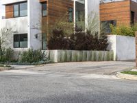 white modern residential house with wood siding and green lawn next to street level paved driveway