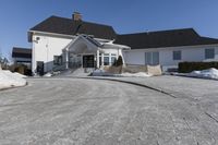 a house in a residential area with snow piled up on the driveway and the sidewalk