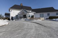 a house in a residential area with snow piled up on the driveway and the sidewalk