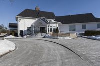 a house in a residential area with snow piled up on the driveway and the sidewalk