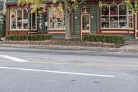 a green building with red, white, and blue decor along a street corner is part of the shop for christmas decor