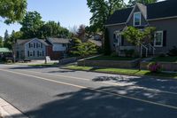 two story houses and a truck parked near a street lined with flowered flowers on grass