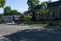 two story houses and a truck parked near a street lined with flowered flowers on grass