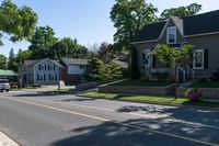 two story houses and a truck parked near a street lined with flowered flowers on grass