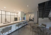 modern kitchen and dining area inside a home with a staircase in the background, there's a table set for four