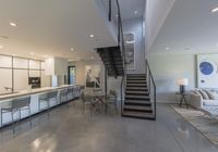 modern kitchen and dining area inside a home with a staircase in the background, there's a table set for four