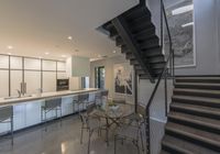 modern kitchen and dining area inside a home with a staircase in the background, there's a table set for four