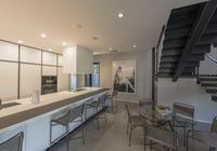 modern kitchen and dining area inside a home with a staircase in the background, there's a table set for four