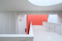 a hallway with an open roof and a red accent wall next to a white staircase