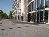 a sidewalk is lined with brick bricks and large windows and doors that lead to some buildings