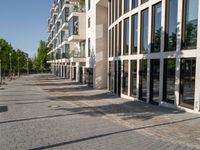 a sidewalk is lined with brick bricks and large windows and doors that lead to some buildings