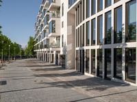 a sidewalk is lined with brick bricks and large windows and doors that lead to some buildings