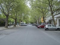 an image of a tree lined city street with a couple of vehicles parked in the driveway