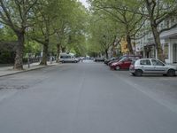 an image of a tree lined city street with a couple of vehicles parked in the driveway