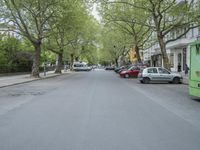 an image of a tree lined city street with a couple of vehicles parked in the driveway