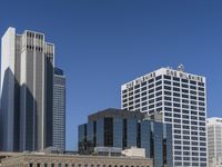 a bunch of high buildings sit near each other on a sunny day and clear blue sky