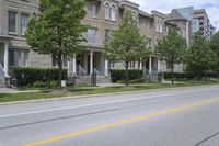 an empty street and some buildings on both sides of the road, with the green grass between the two trees